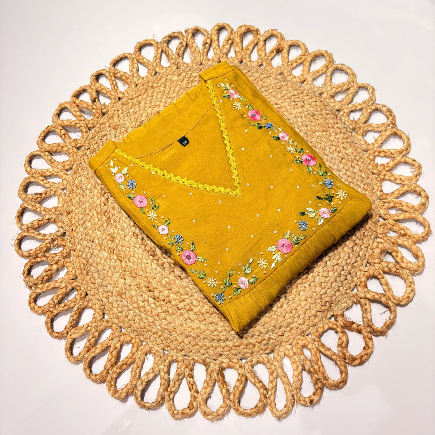Mustard yellow embroidered fabric on a woven placemat