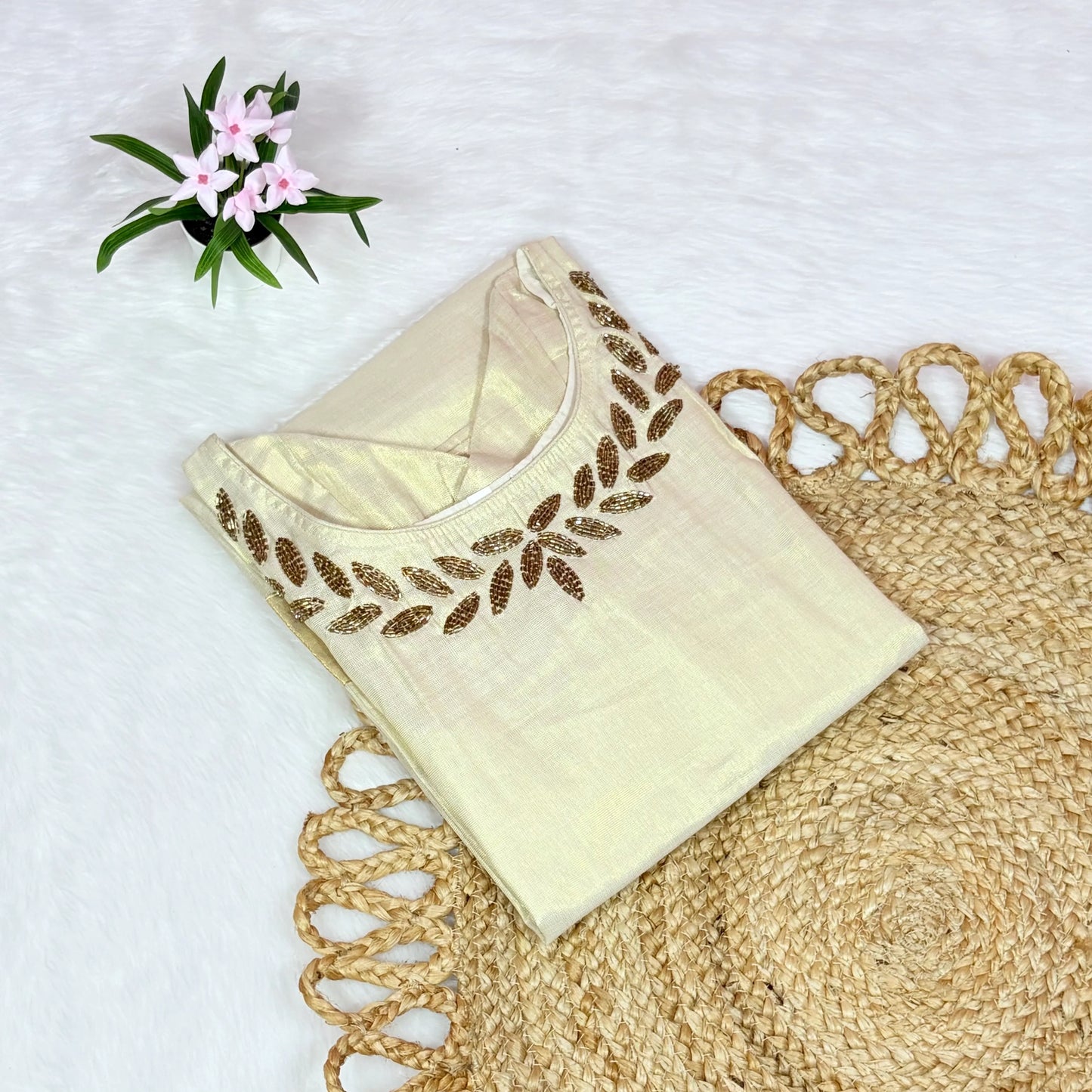 Beige blouse with floral embroidery on a textured surface with flowers in the background