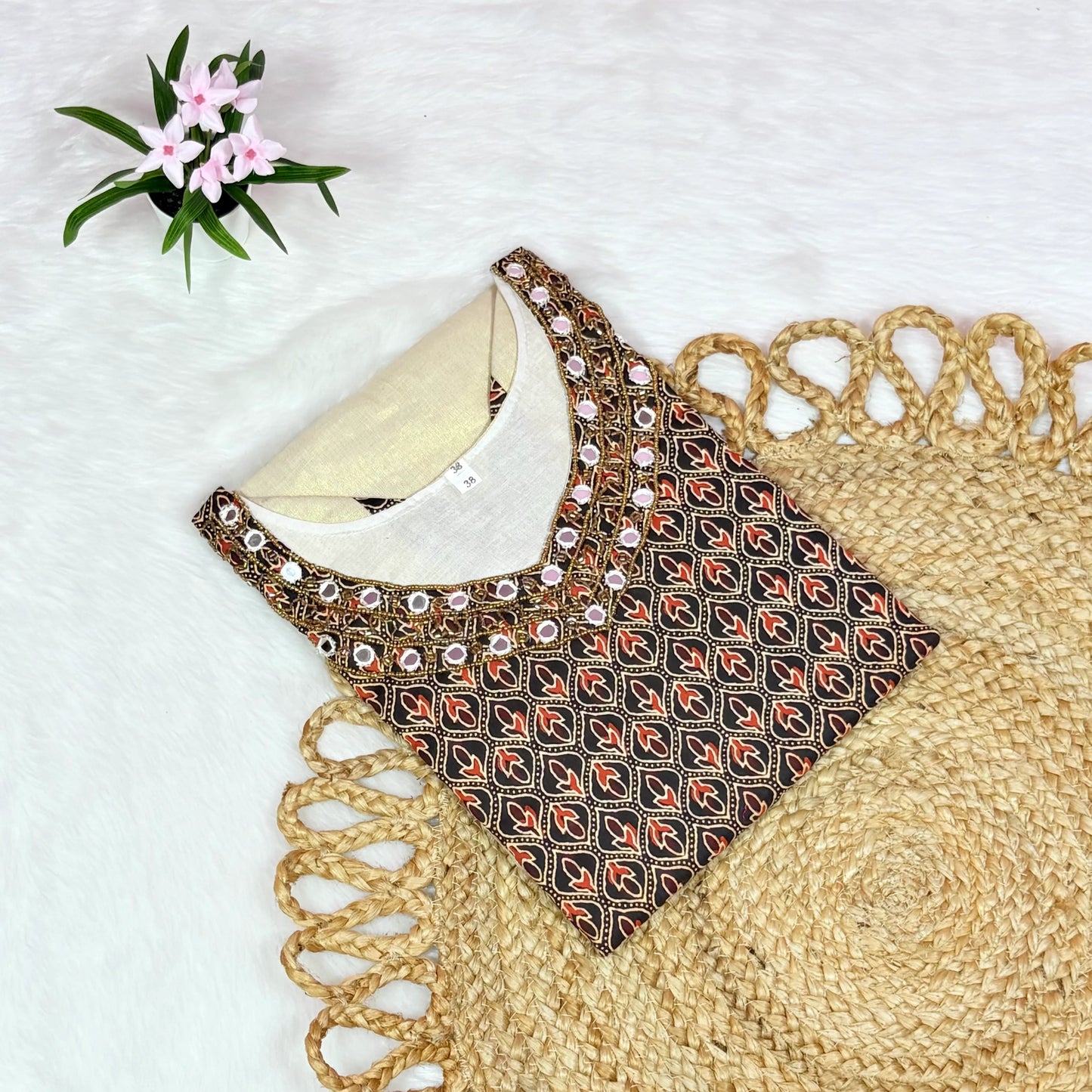 Embroidered blouse with a geometric pattern on a textured surface with flowers.