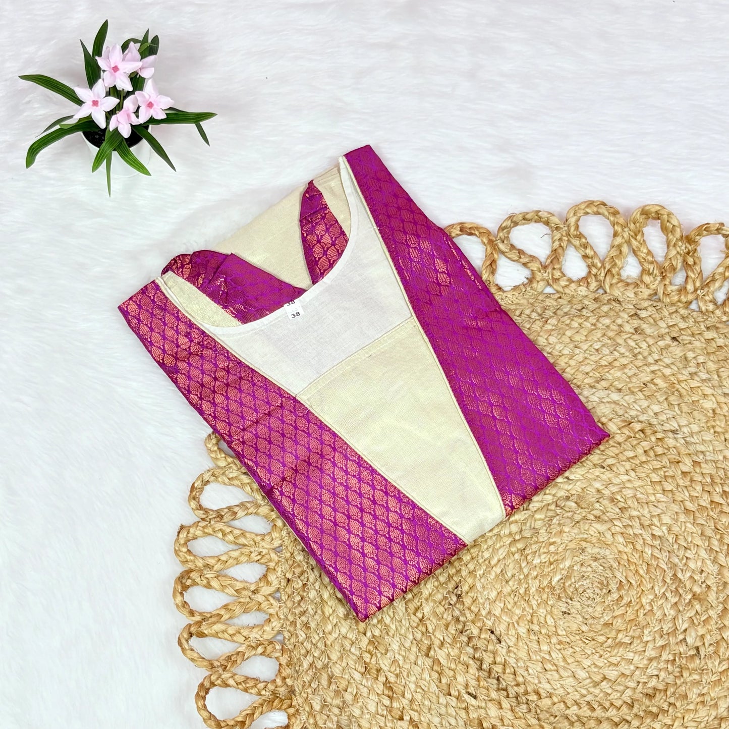 Purple and beige blouse on a textured surface with flowers in the corner