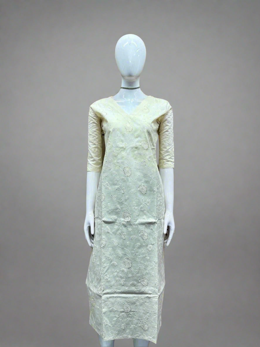 Mannequin wearing a light-colored dress against a geometric patterned wall.
