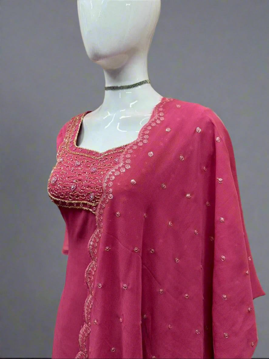 Pink embroidered traditional outfit on a mannequin against a geometric patterned wall.
