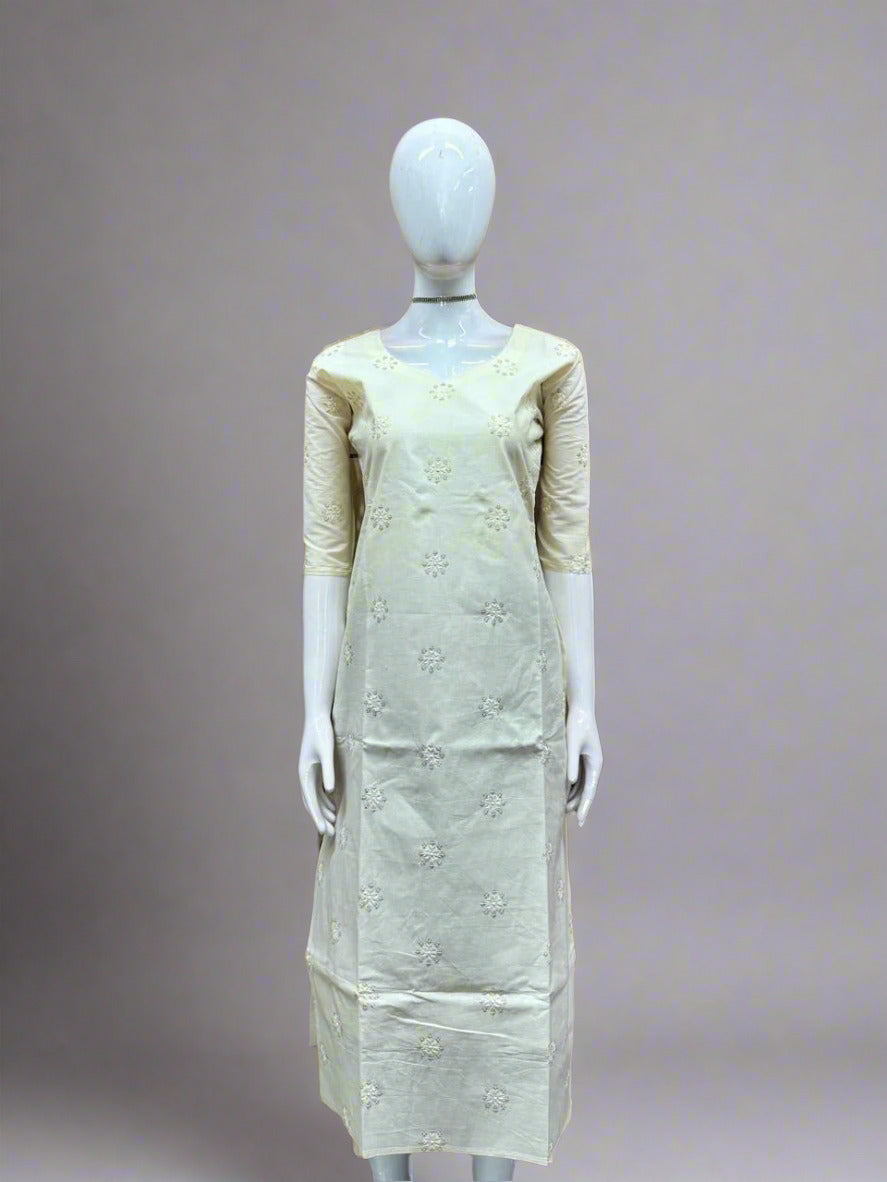 Mannequin wearing a light-colored dress with floral patterns against a geometric patterned wall.