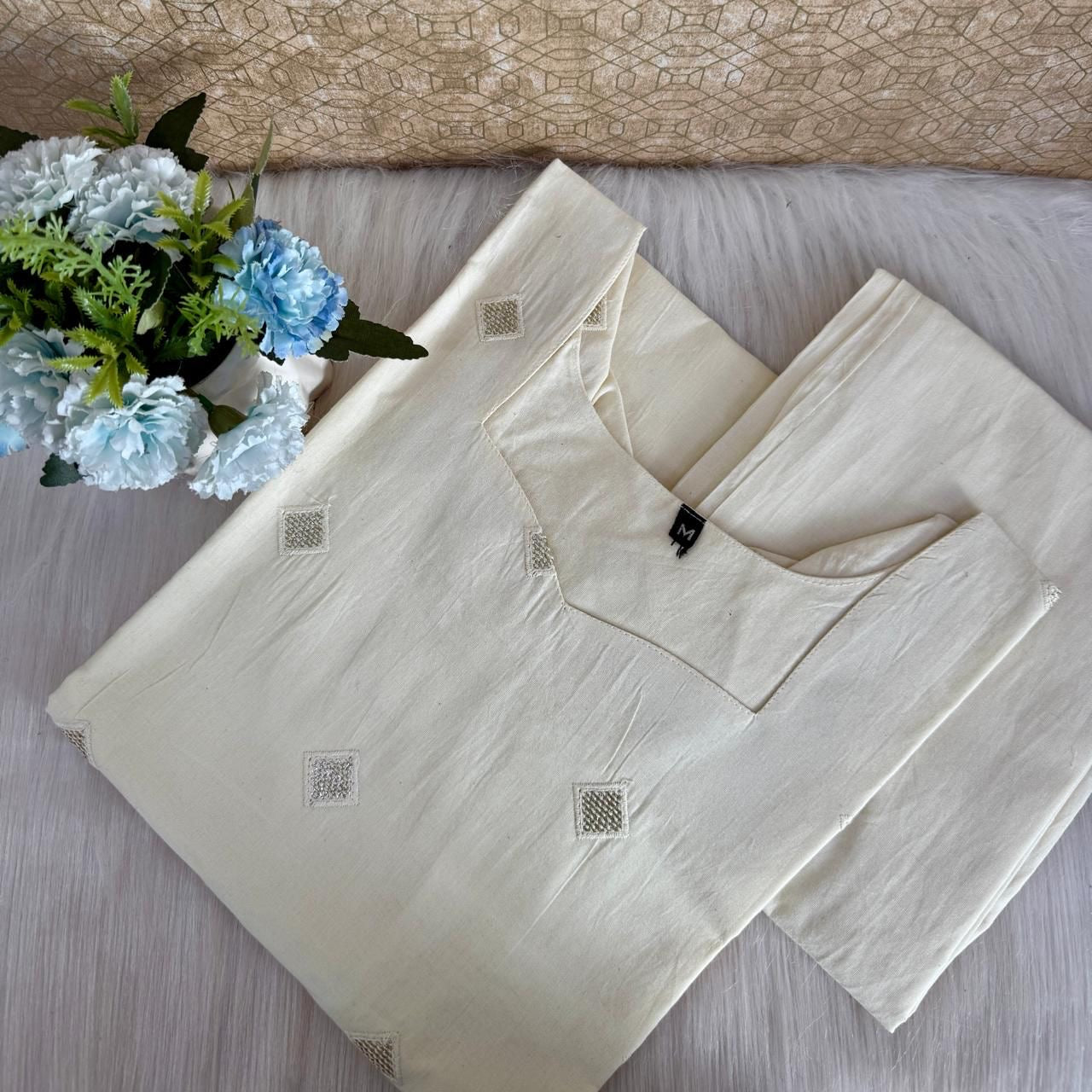 Beige outfit with floral arrangement on a textured surface