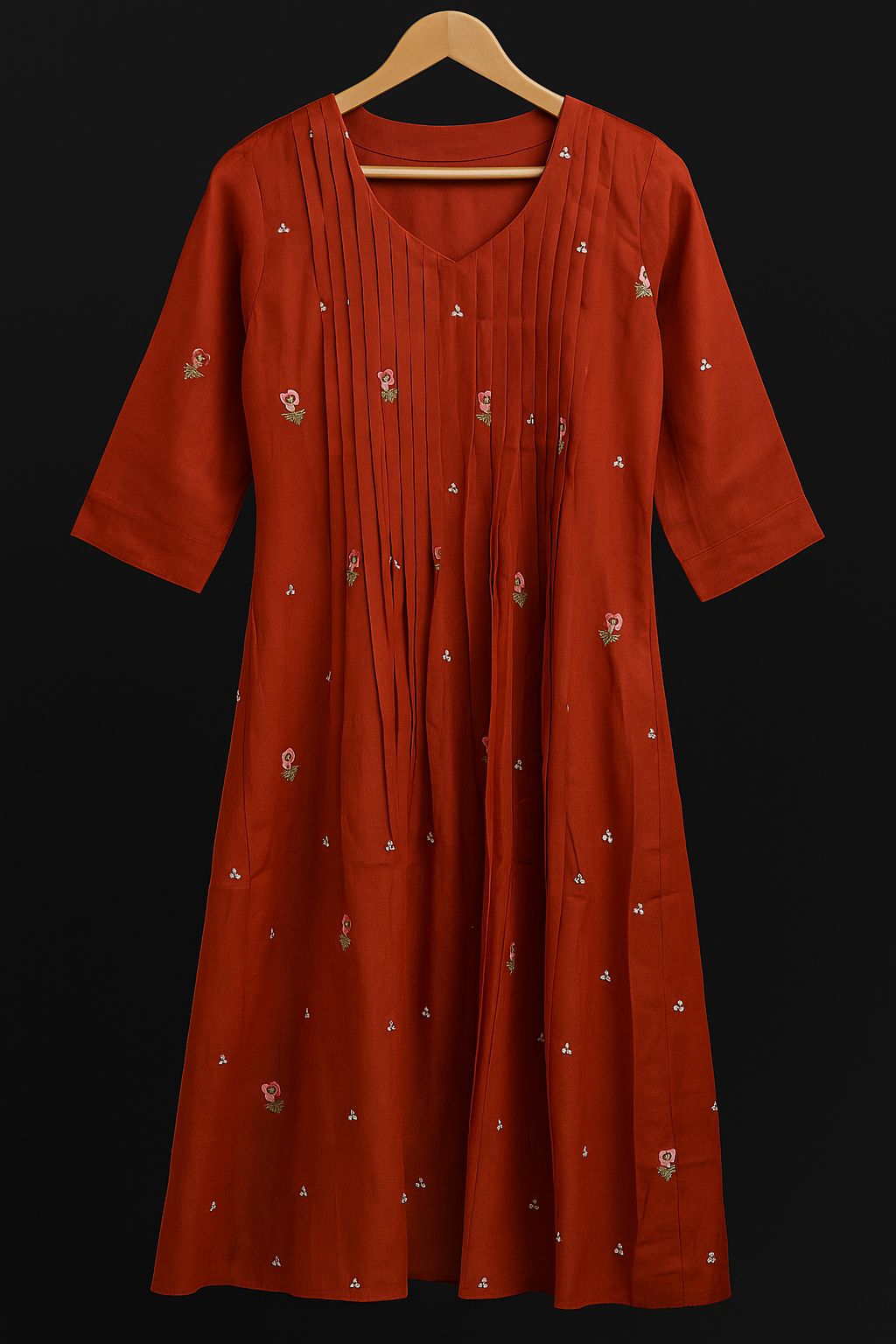 Red dress with white patterns on a hanger against a black background