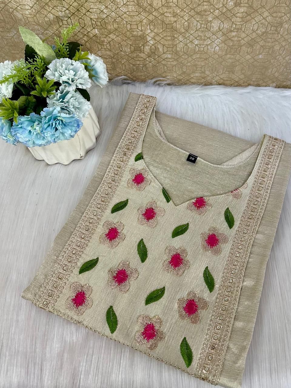 Beige embroidered garment with pink flowers on a textured surface with flowers in the background