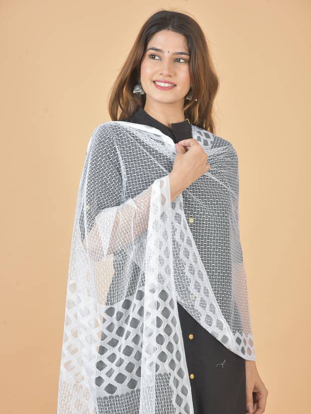 Woman wearing a white and gray patterned shawl against a beige background