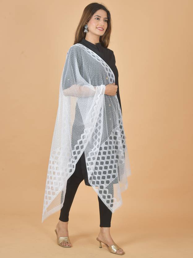 Woman wearing a white patterned shawl over a black outfit on a beige background