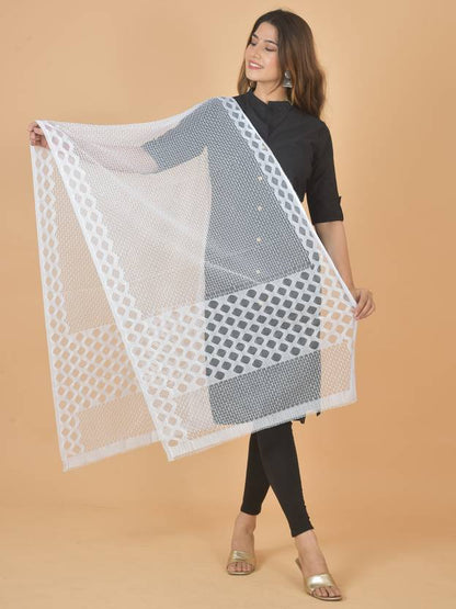 Woman holding a large white and gray patterned scarf against a beige background