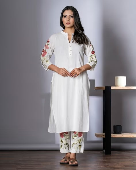 Woman wearing a white kurta with floral patterns in a minimalistic setting