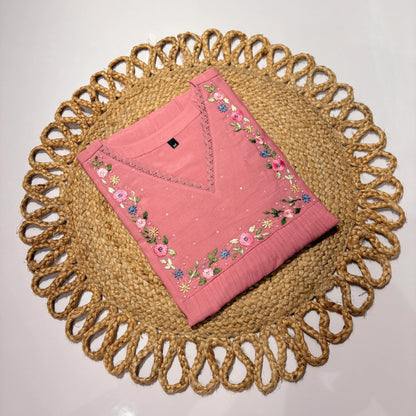 Pink embroidered fabric on a woven placemat with a plain background