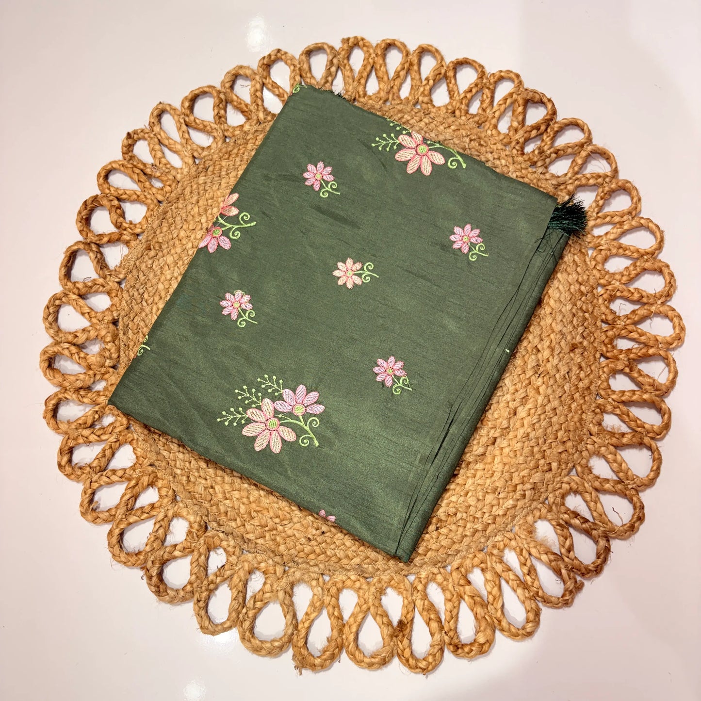 Green embroidered fabric on a woven placemat