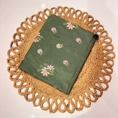Green embroidered fabric on a woven placemat