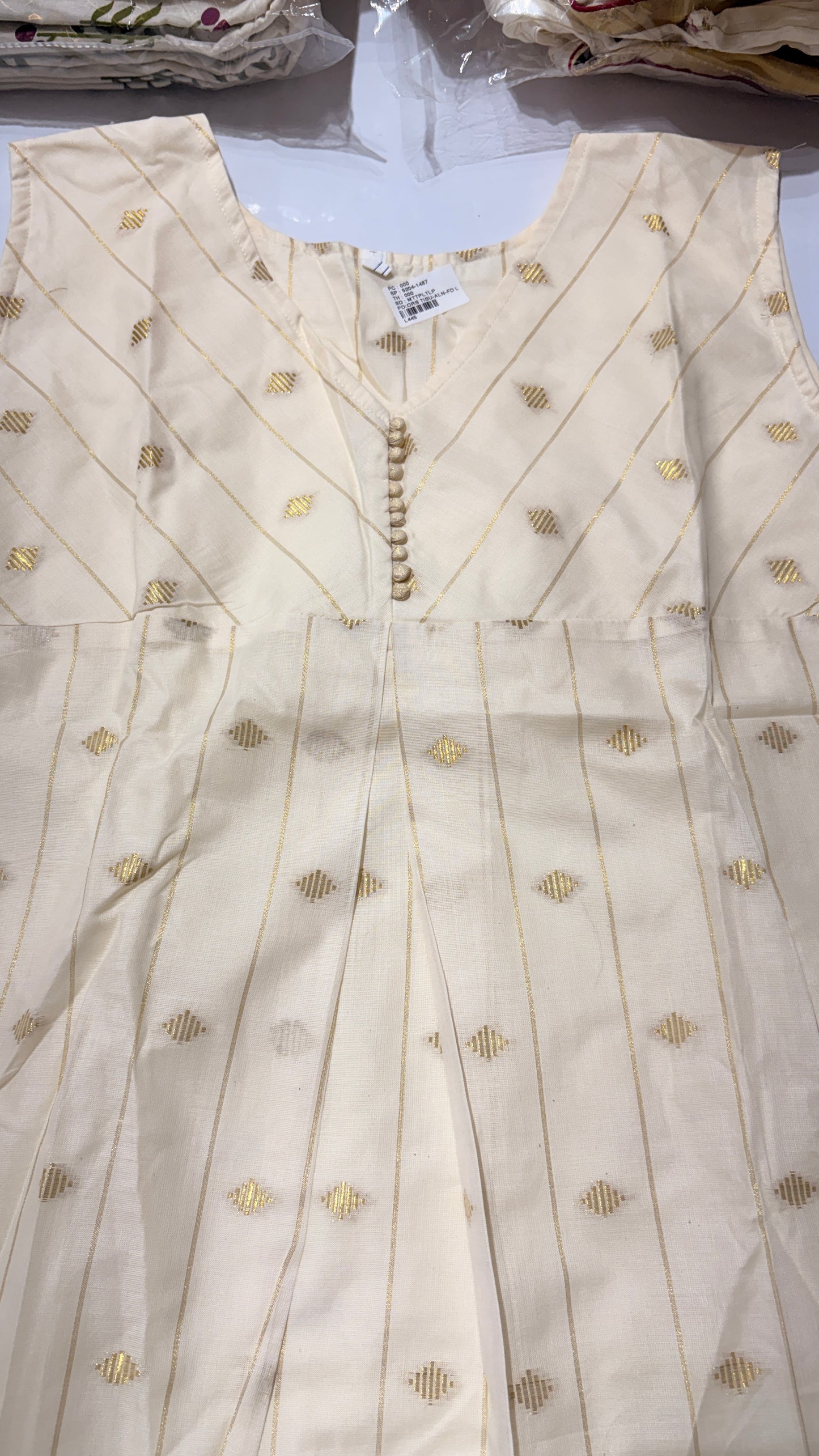 Close-up of diagonal yoke seaming, pearl button placket and scattered gold diamond butti motifs on cream digital print tissue kurti with gold lurex stripes – RAE Trends