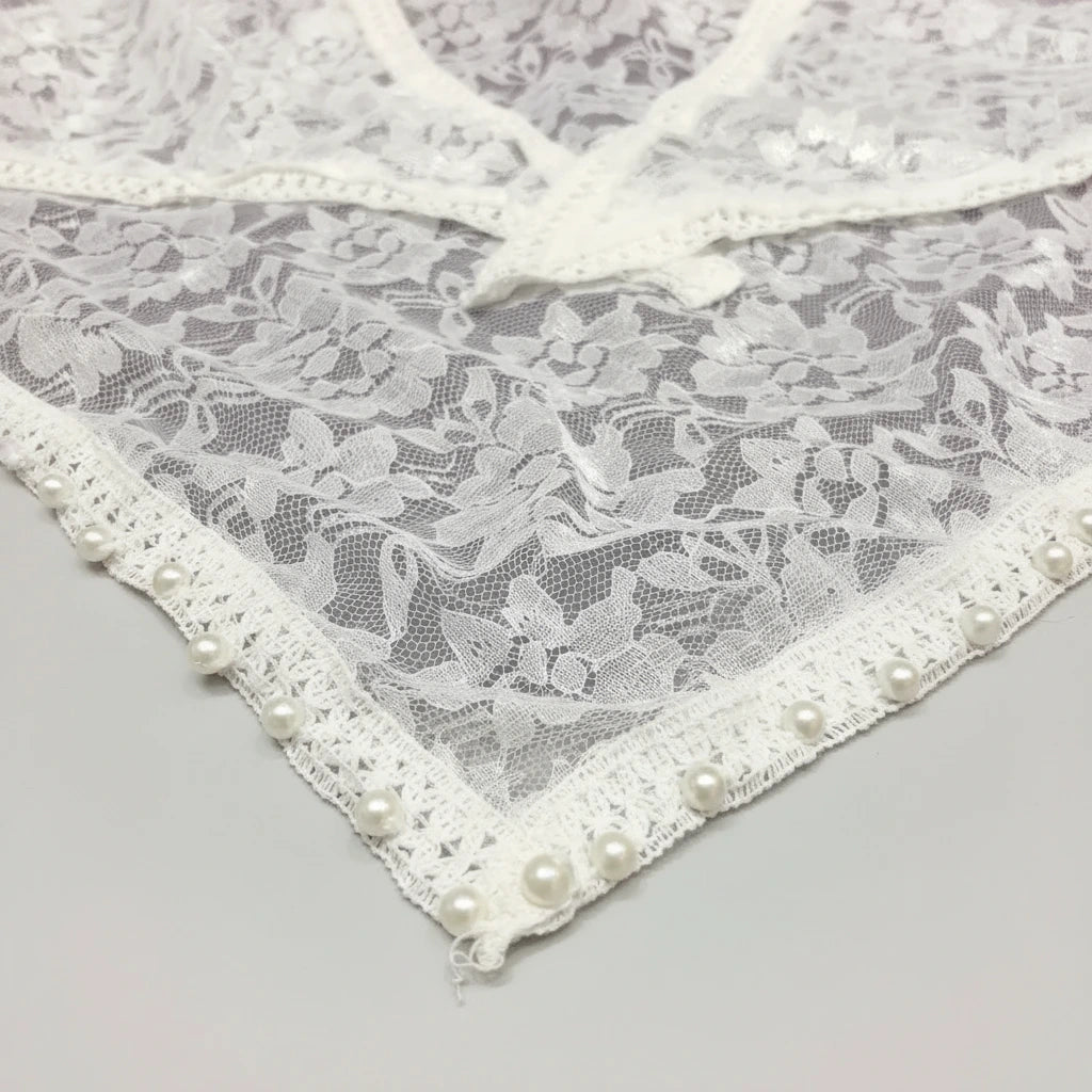 Lace fabric with pearl embellishments on a gray background