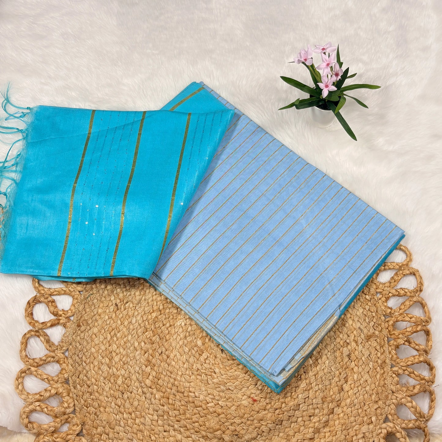 Aqua blue Bapta Tussar silk saree with woven zari lines, subtle sequin accents, tasselled pallu, and matching blouse piece, folded on a natural mat