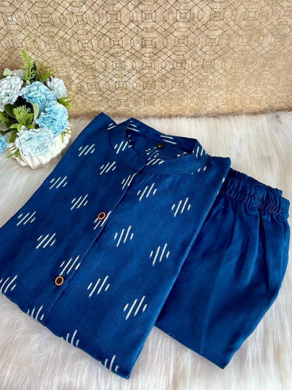 Blue pants with white patterns on a light wooden surface with a woven mat and flowers in the background.