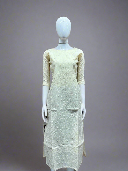 Mannequin wearing a light-colored dress against a geometric patterned wall.