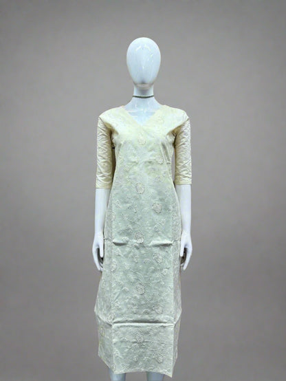 Mannequin wearing a light-colored dress against a geometric patterned wall.