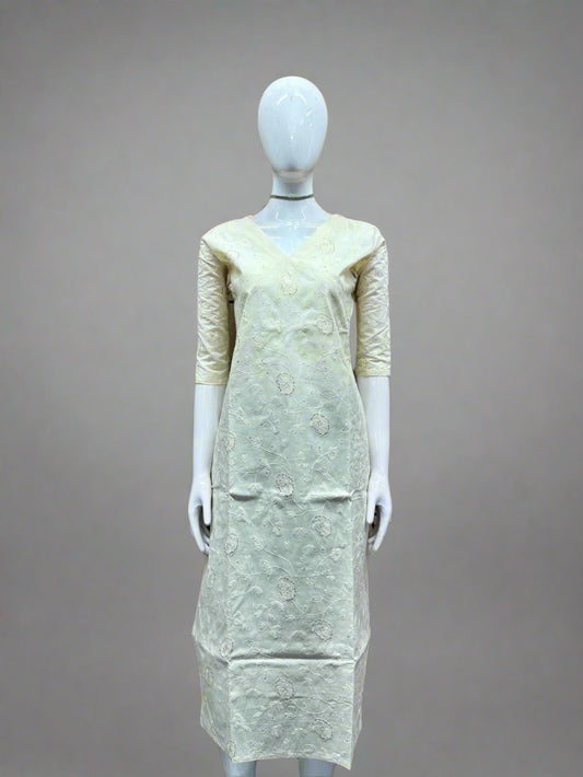 Mannequin wearing a light-colored dress against a geometric patterned wall.