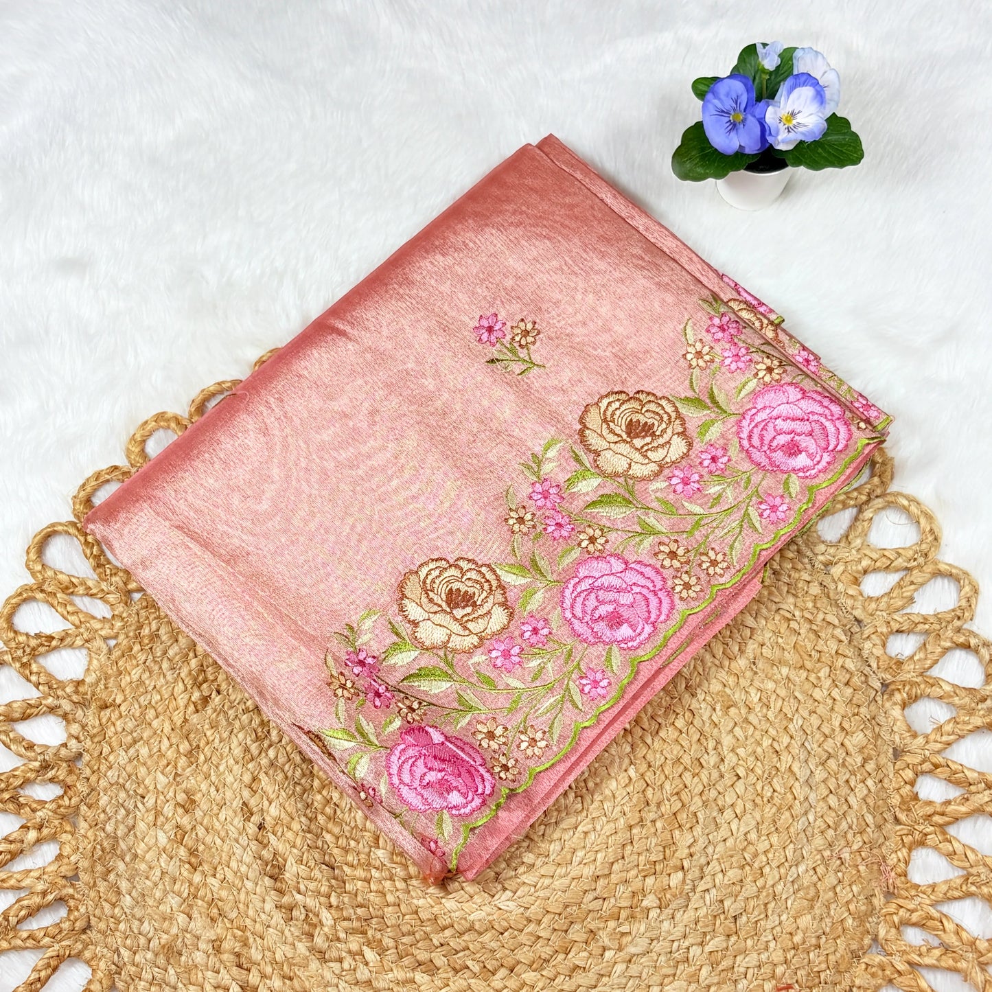 Pink embroidered fabric with floral patterns on a textured surface