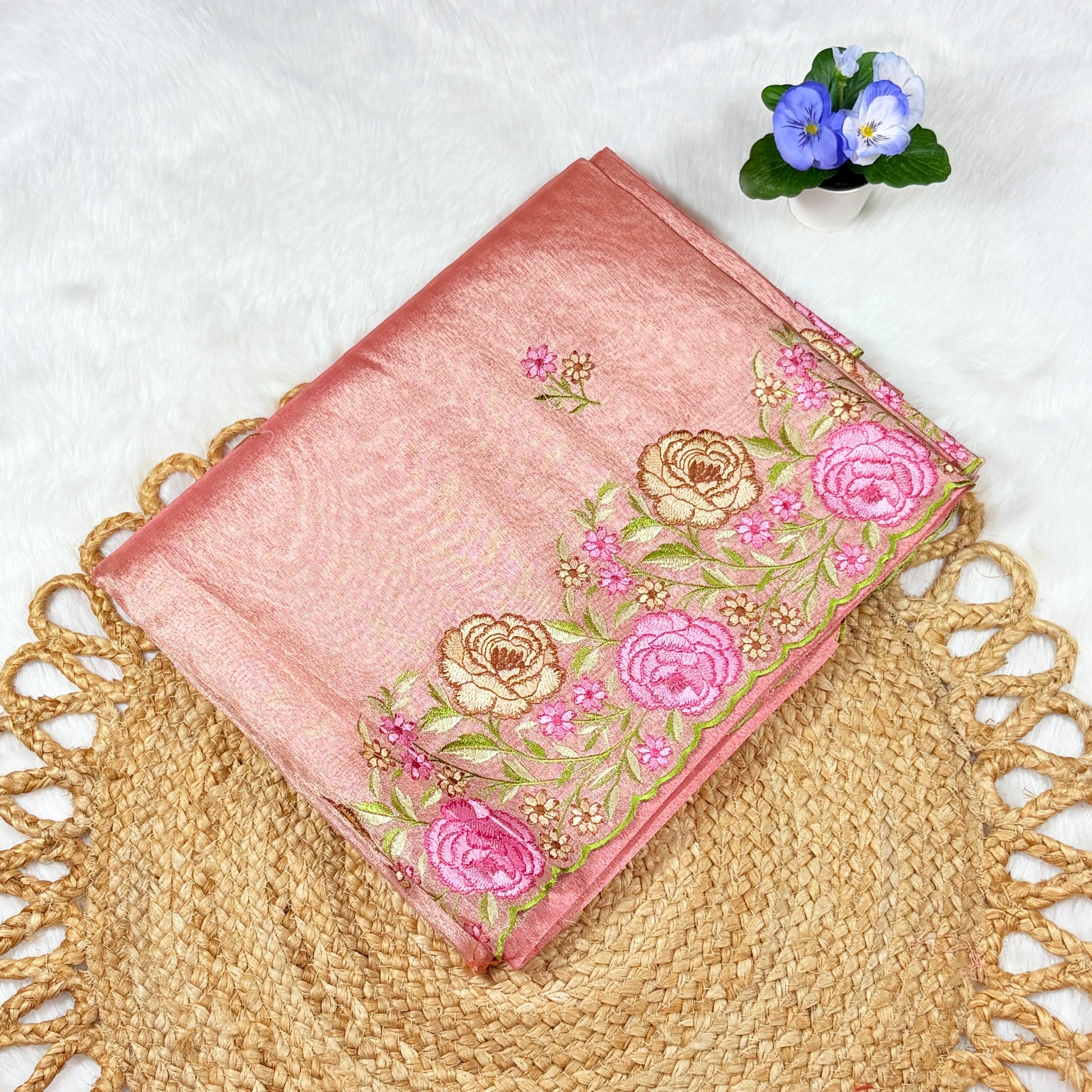 Pink embroidered fabric with floral patterns on a textured surface