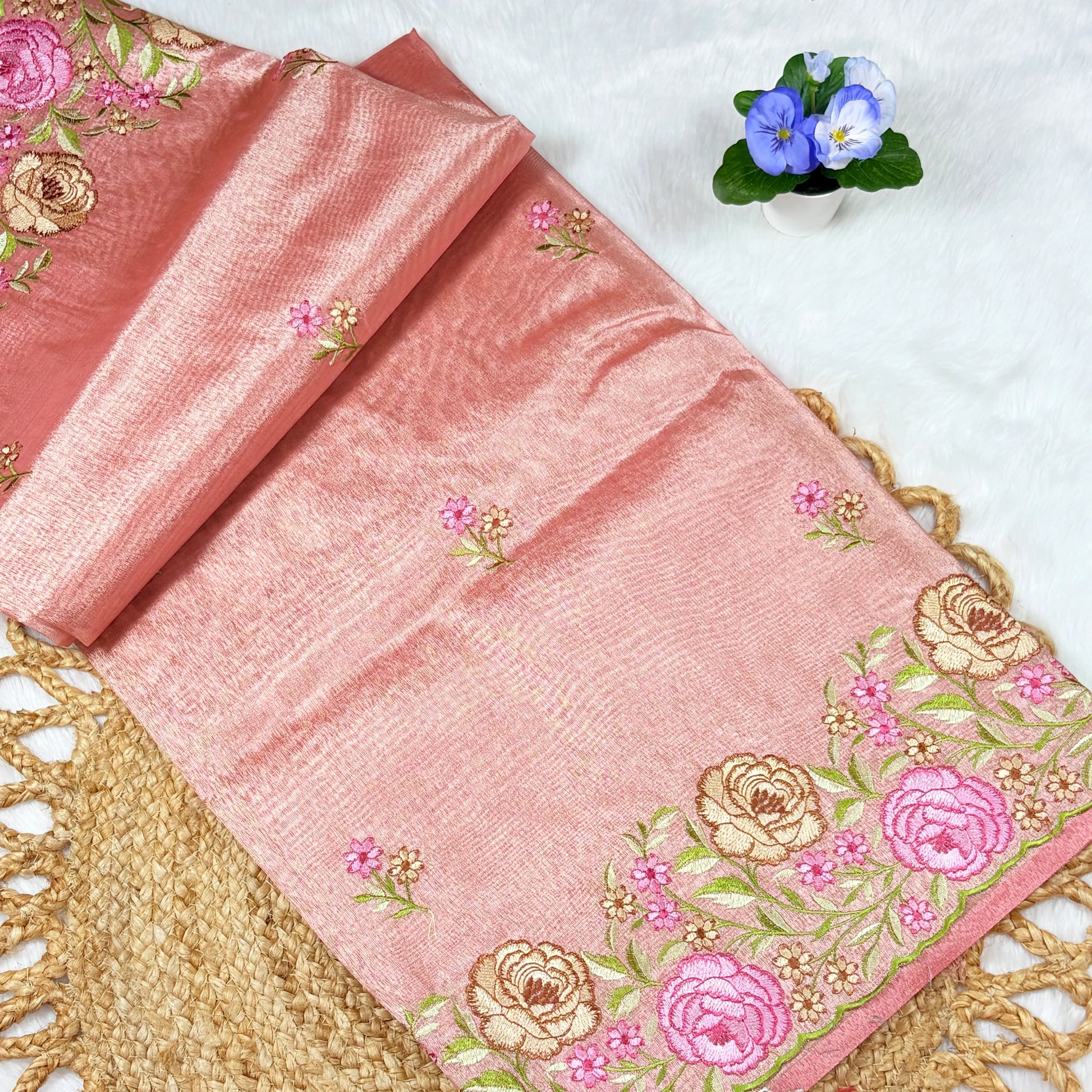 Pink fabric with floral embroidery on a textured surface