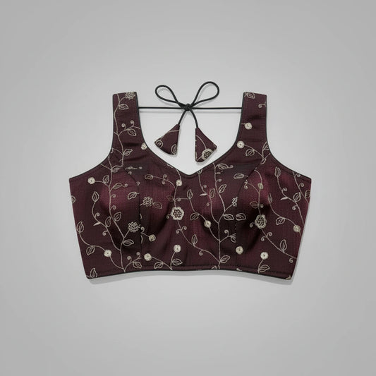 Maroon embroidered lingerie set on a decorative woven mat with a blue background