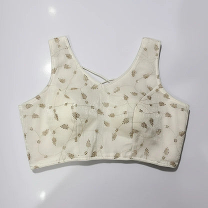 White embroidered top on a woven placemat with a white background