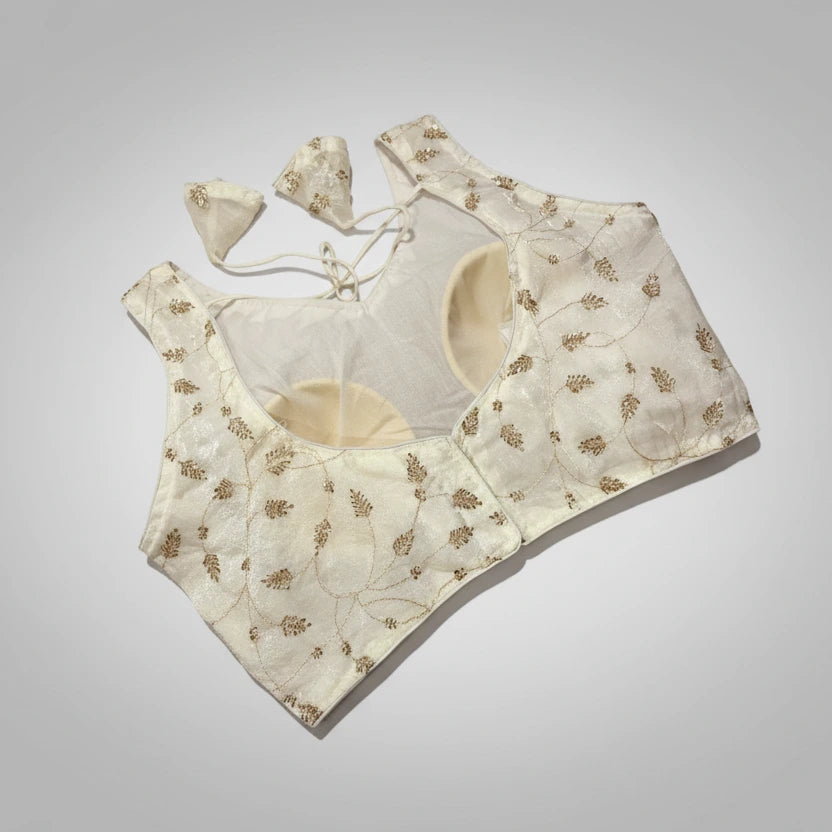 Embroidered white blouse with gold patterns on a woven placemat