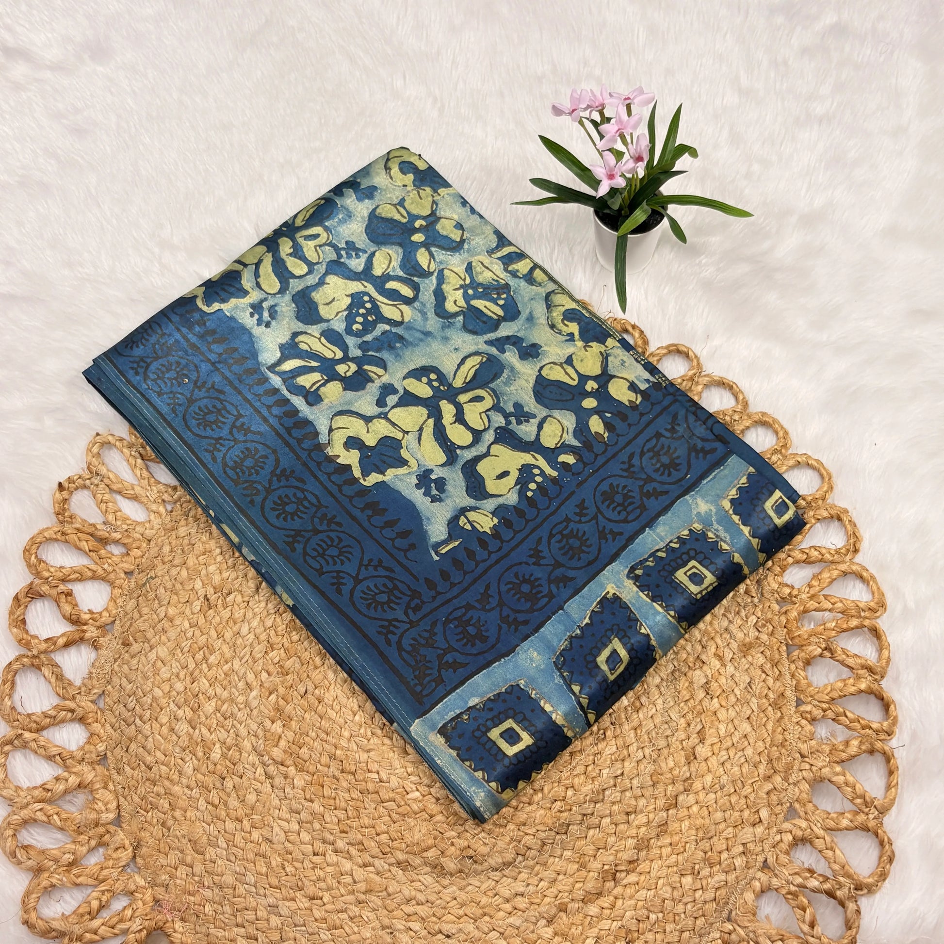 Blue and green patterned towel on a woven mat with a small plant