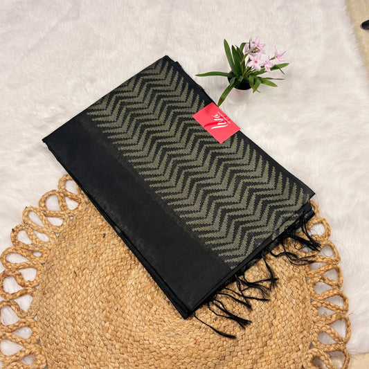 Black and green patterned scarf with a brand tag on a textured surface
