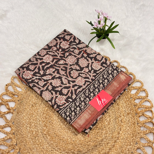 Maheshwari Bagru block print saree in deep brown with ivory floral vines, rust‑gold border, tasselled pallu, and matching blouse piece