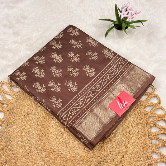 Cocoa‑brown Maheshwari art silk saree with beige floral buta, vine border, soft gold zari panel, and matching blouse piece