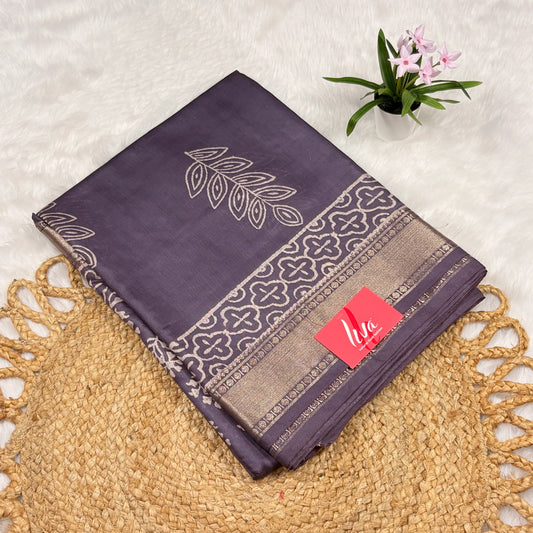 Slate‑purple Maheshwari art silk saree with floral buta, bold leaf pallu motif, trellis borders, soft gold zari band, and matching blouse piece