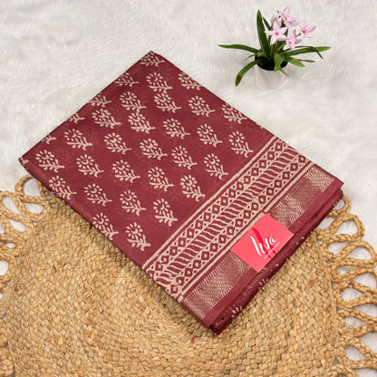 Maroon Maheshwari art silk saree with beige floral buta, geometric vine borders, soft gold zari band, and matching blouse piece