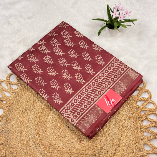 Maroon Maheshwari art silk saree with beige floral buta, geometric vine borders, soft gold zari band, and matching blouse piece