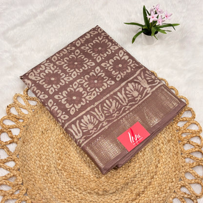 Mauve‑taupe Maheshwari Dabu block print saree with light beige floral blocks, soft gold zari border, tasselled pallu, and matching blouse piece