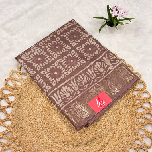 Mauve‑taupe Maheshwari Dabu block print saree with light beige floral blocks, soft gold zari border, tasselled pallu, and matching blouse piece