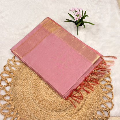 Pink saree with gold border and red fringes on a textured surface