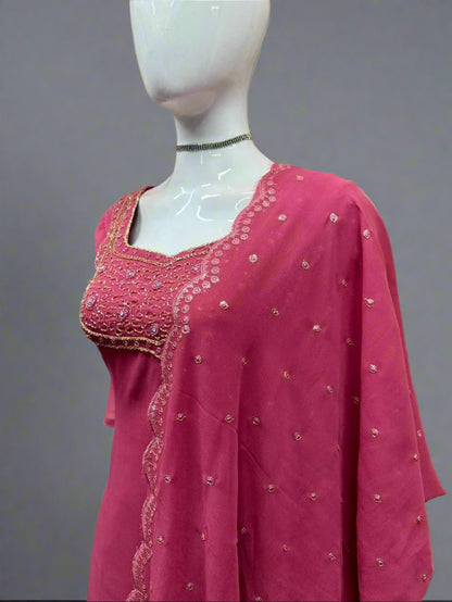 Pink embroidered traditional outfit on a mannequin against a geometric patterned wall.