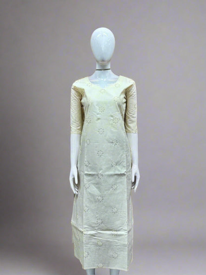 Mannequin wearing a light-colored dress with floral patterns against a geometric patterned wall.