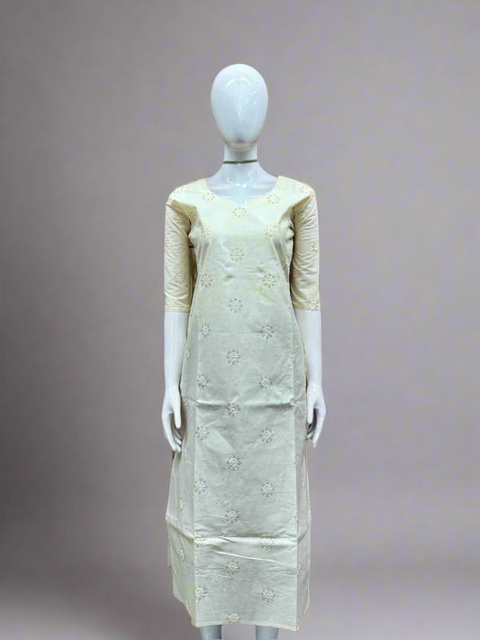 Mannequin wearing a light-colored dress with floral patterns against a geometric patterned wall.