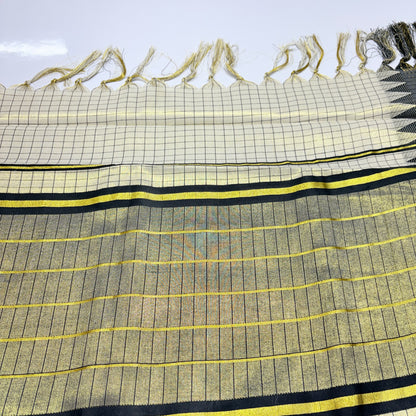 Close-up of Kerala tissue silk saree showing gold shimmer check weave body with fine black grid lines, yellow zari horizontal stripes on pallu, bold black and gold stripe border, and cream check body with gold tassel fringe – Onam and wedding wear