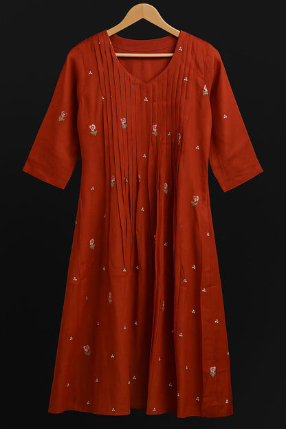 Red dress with white patterns on a hanger against a black background