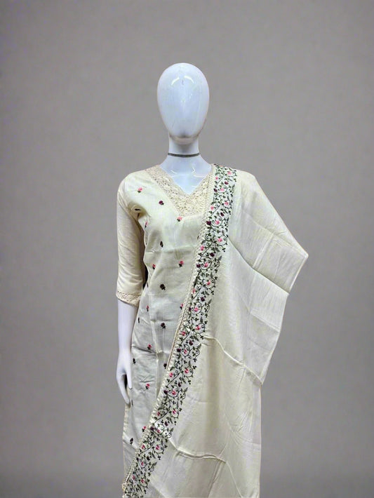 Mannequin wearing a cream saree with intricate patterns against a geometric patterned wall.