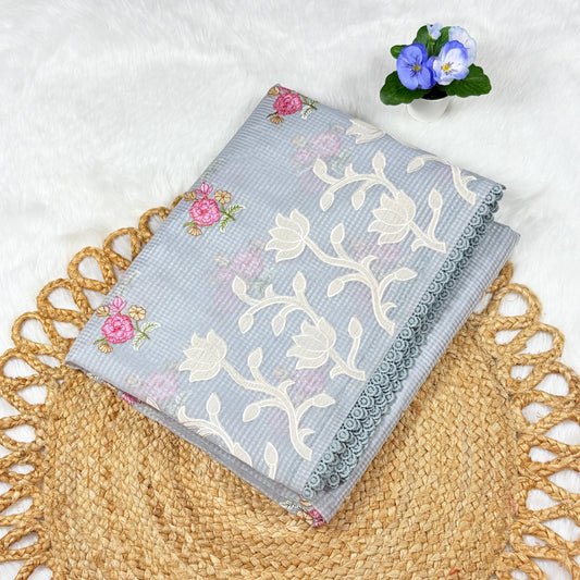 Floral embroidered fabric on a textured surface with a small potted plant.