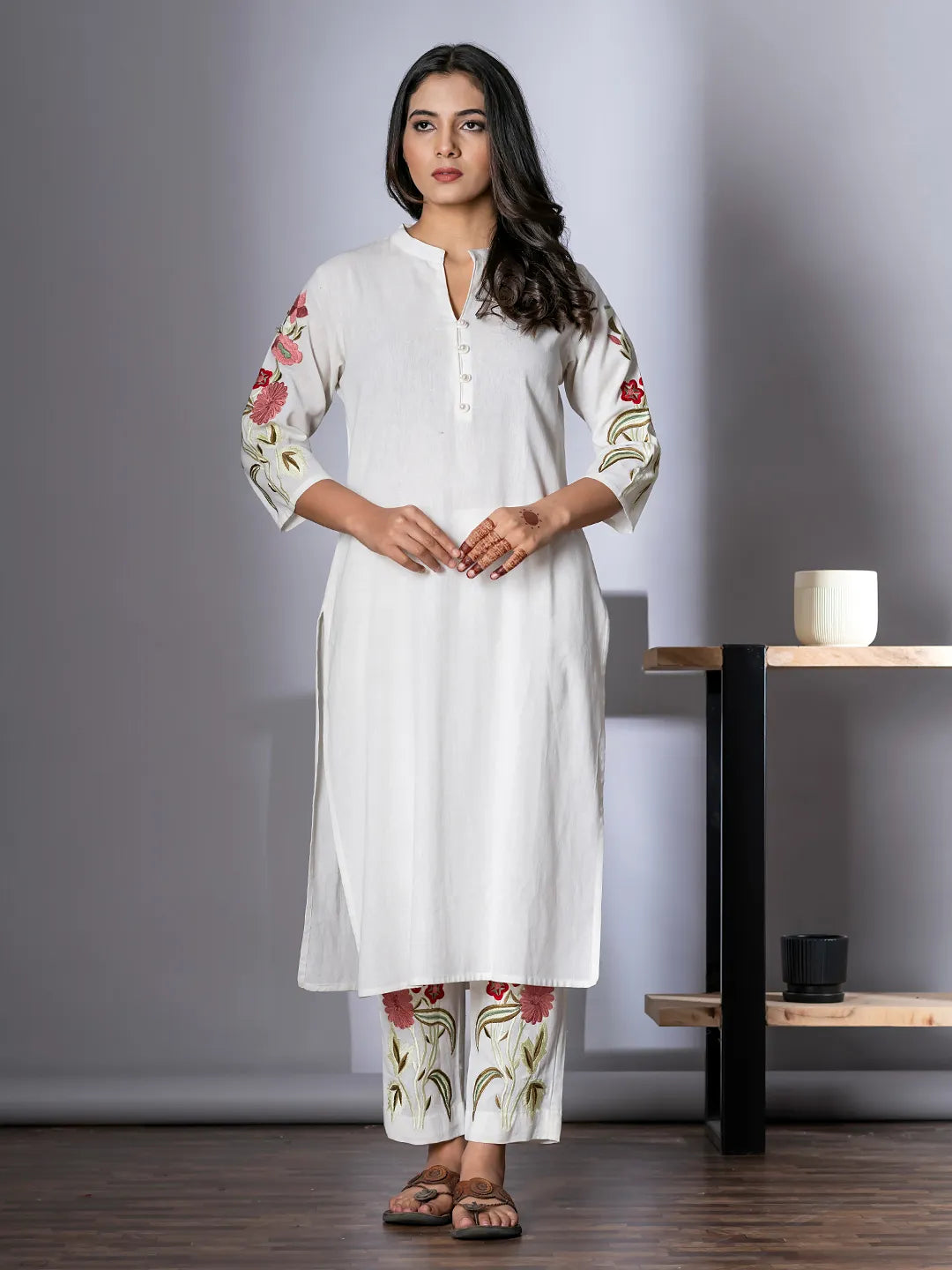 Woman wearing a white kurta with floral embroidery in a minimalistic setting