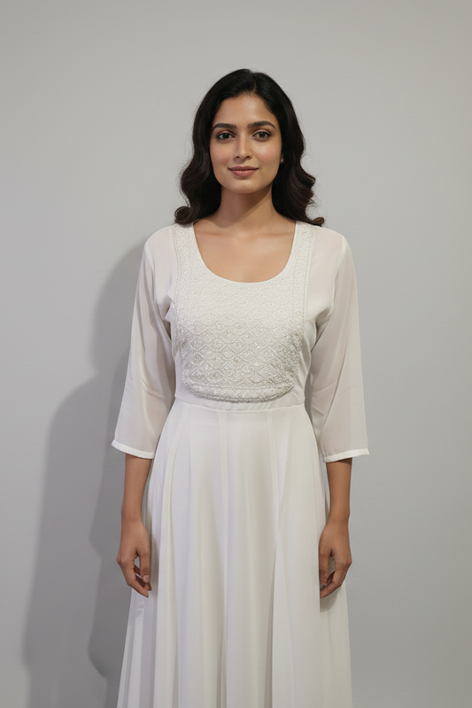 Woman wearing a white dress with a textured top against a neutral background