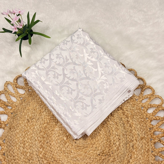 White floral-patterned fabric on a textured surface with a small plant.